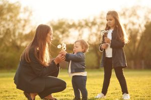 Mom with two young daughters playing in a field.