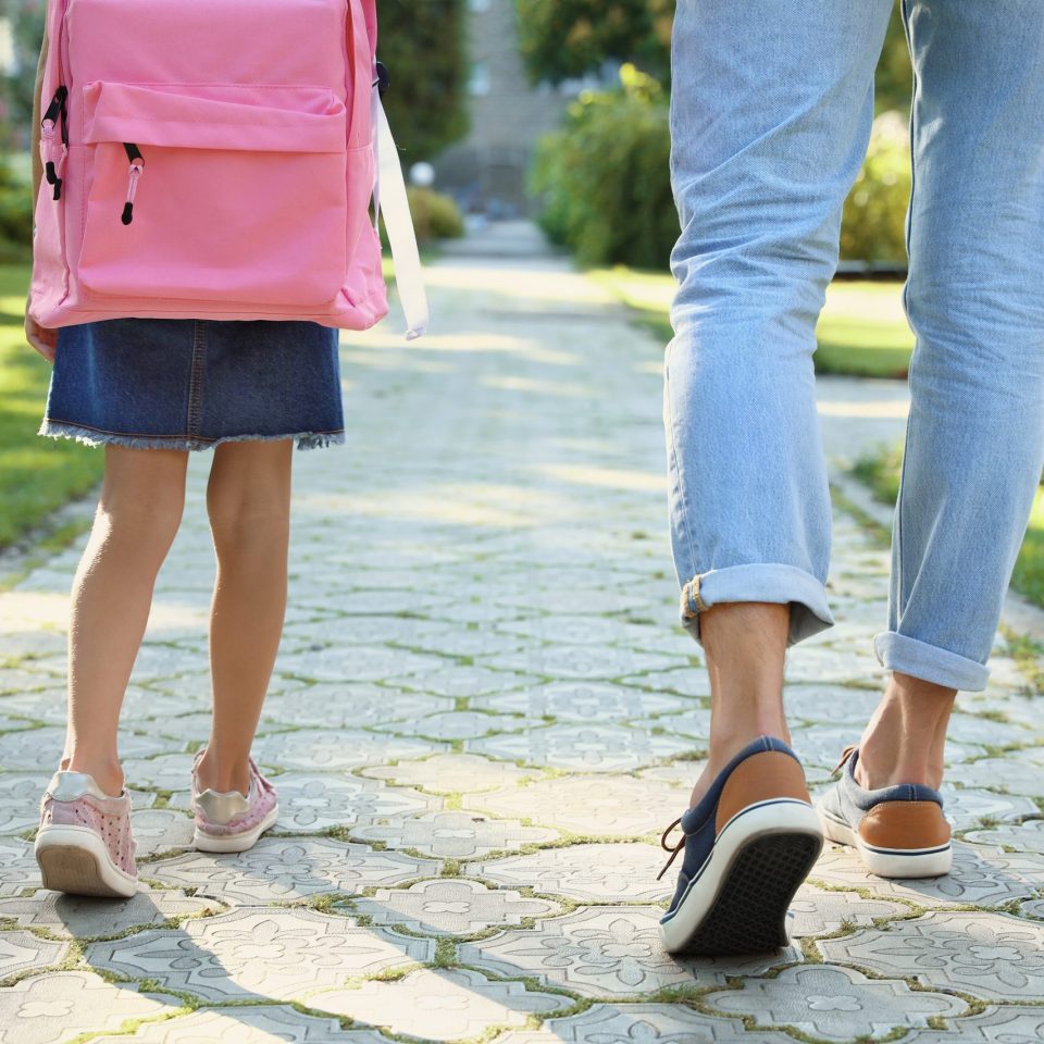 Father taking his little child to school through park, closeup